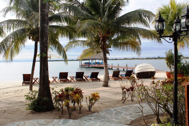 The private beach with palms, loungers and the pier reaching out to sea, Chabil Mar Resort