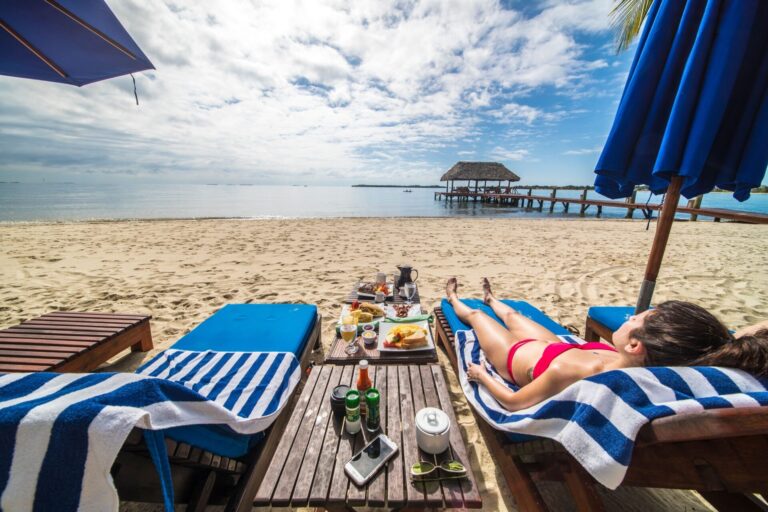 Striped beach loungers on the sand with the pier and the sea beyond, Chabil Mar Resort