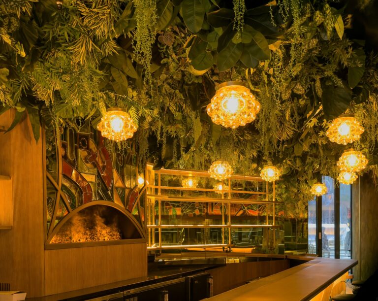 A hanging greenery installation above a restaurant fireplace, Chantal Flores Design
