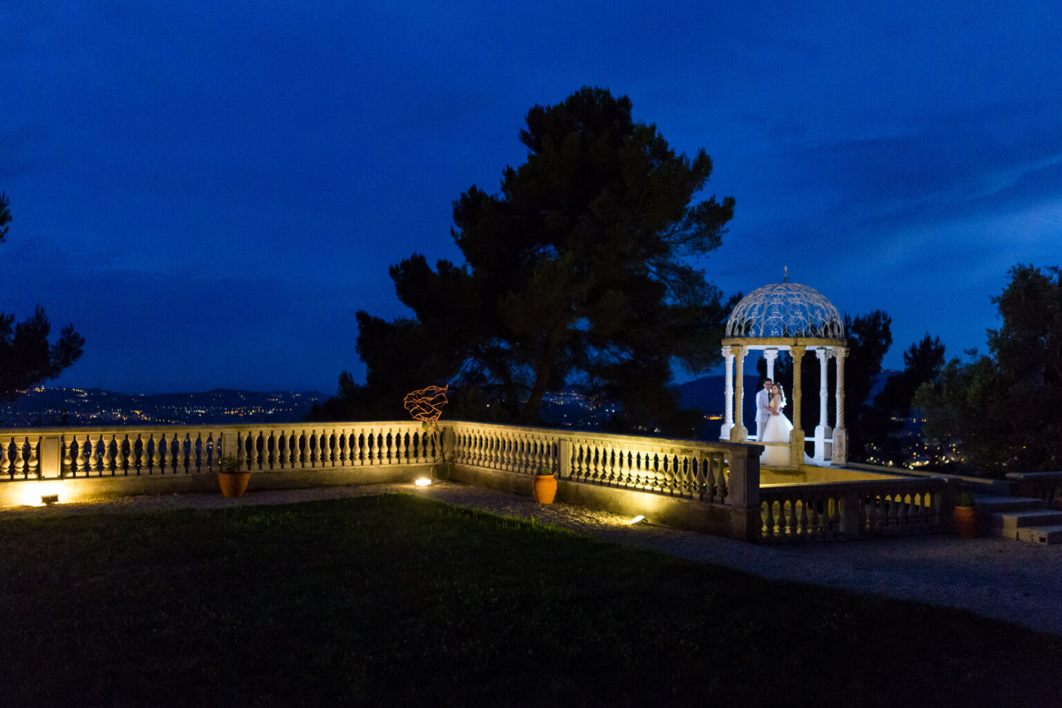 The Temple of Love lit at night across the lawn