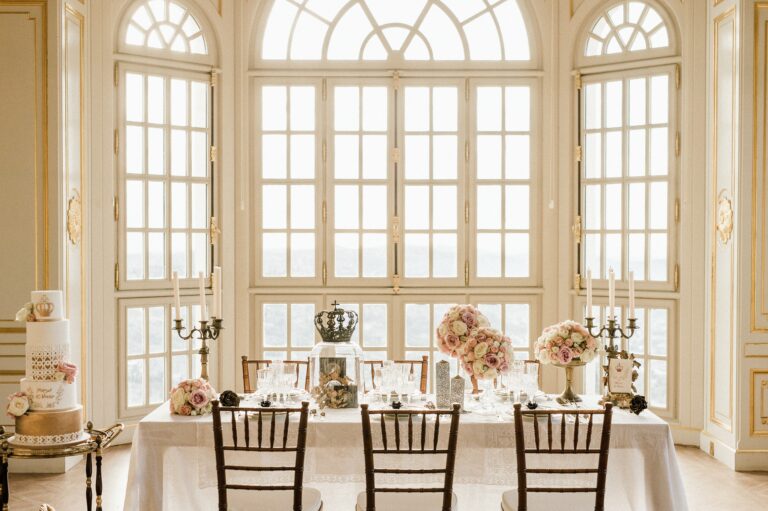A dining table and cake in front of the arched salon windows, Chateau Saint Georges