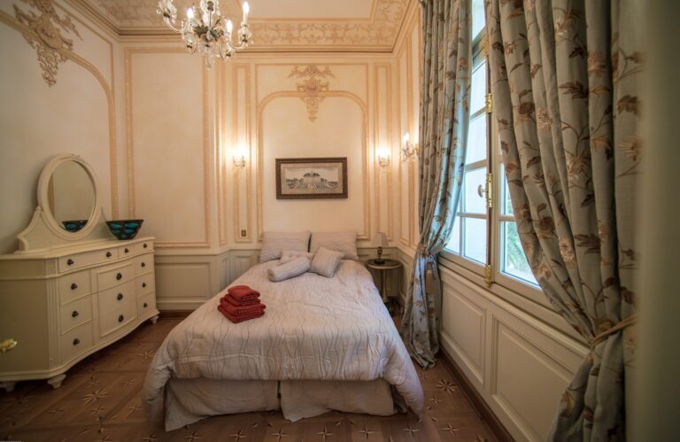 A bedroom with a dressing table and long curtains, Chateau Saint Georges