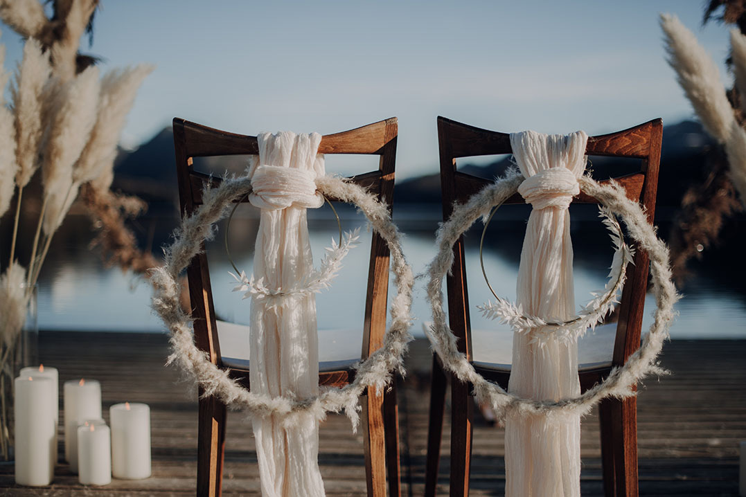 Two chairs dressed with wreaths and drape on a lakeside jetty, candles at their feet, Cherry On Top