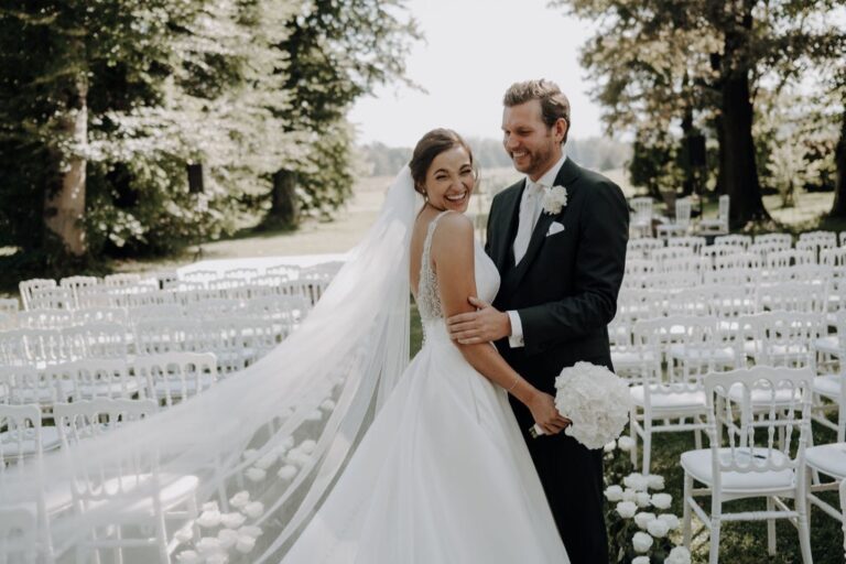 Bride and groom with a long veil in front of rows of white ceremony chairs, Cherry On Top
