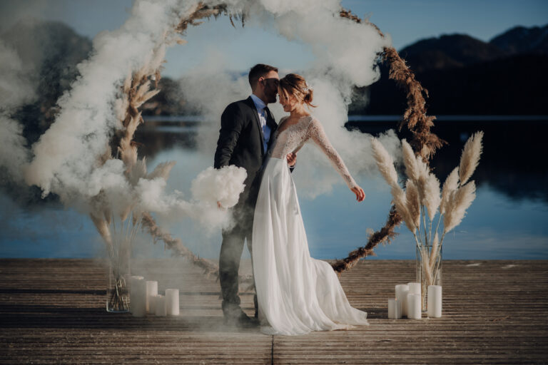 Couple beneath a ring arch with white smoke on a lakeside jetty, Cherry On Top
