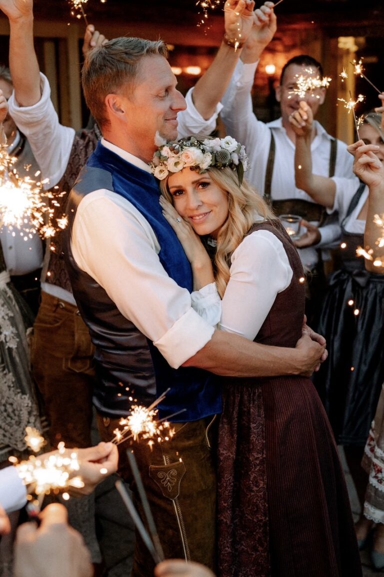 Couple in Tracht embracing among guests holding sparklers, Cherry On Top