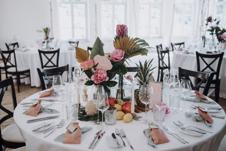 Round table with tropical florals, pink napkins and fruit in a light dining room, Cherry On Top