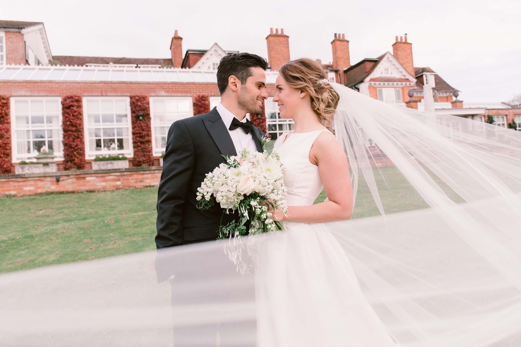 The bride and groom on the lawn with the hotel behind, Chewton Glen Hotel & Spa