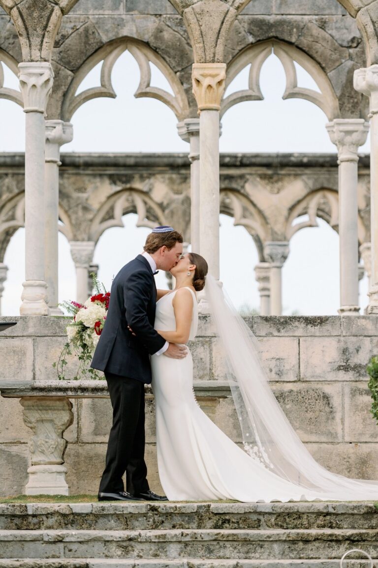 Couple kissing before the stone arches of a ruined cloister, Chic Bahamas Weddings