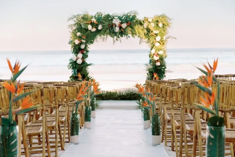 Beach ceremony with a tropical floral arch, bird of paradise and wooden chairs, Chic Bahamas Weddings