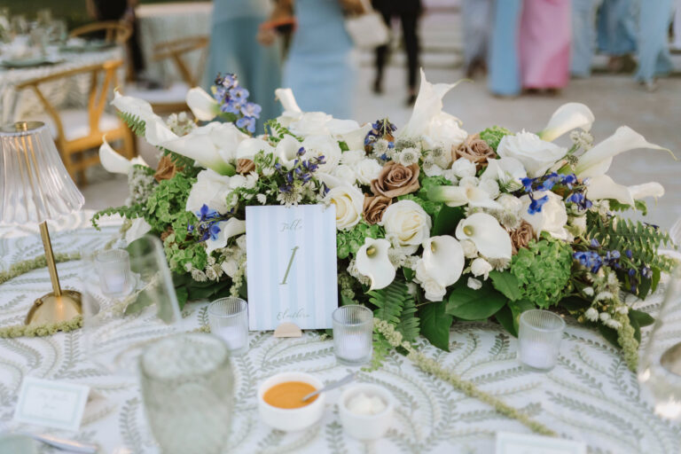 Table centrepiece of white calla lilies, roses and greenery with a table number, Chic Bahamas Weddings