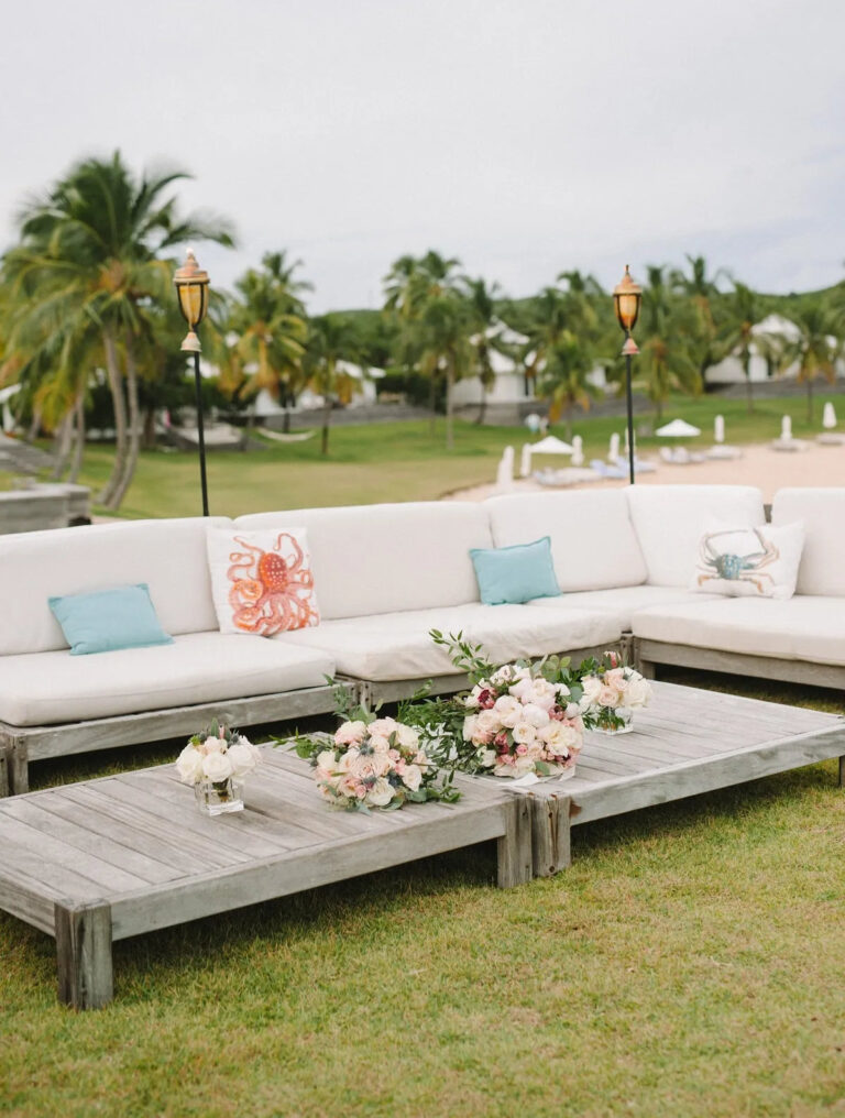 Lounge seating with floral arrangements on the lawn of a resort, palms and tiki torches behind, Chic Bahamas Weddings
