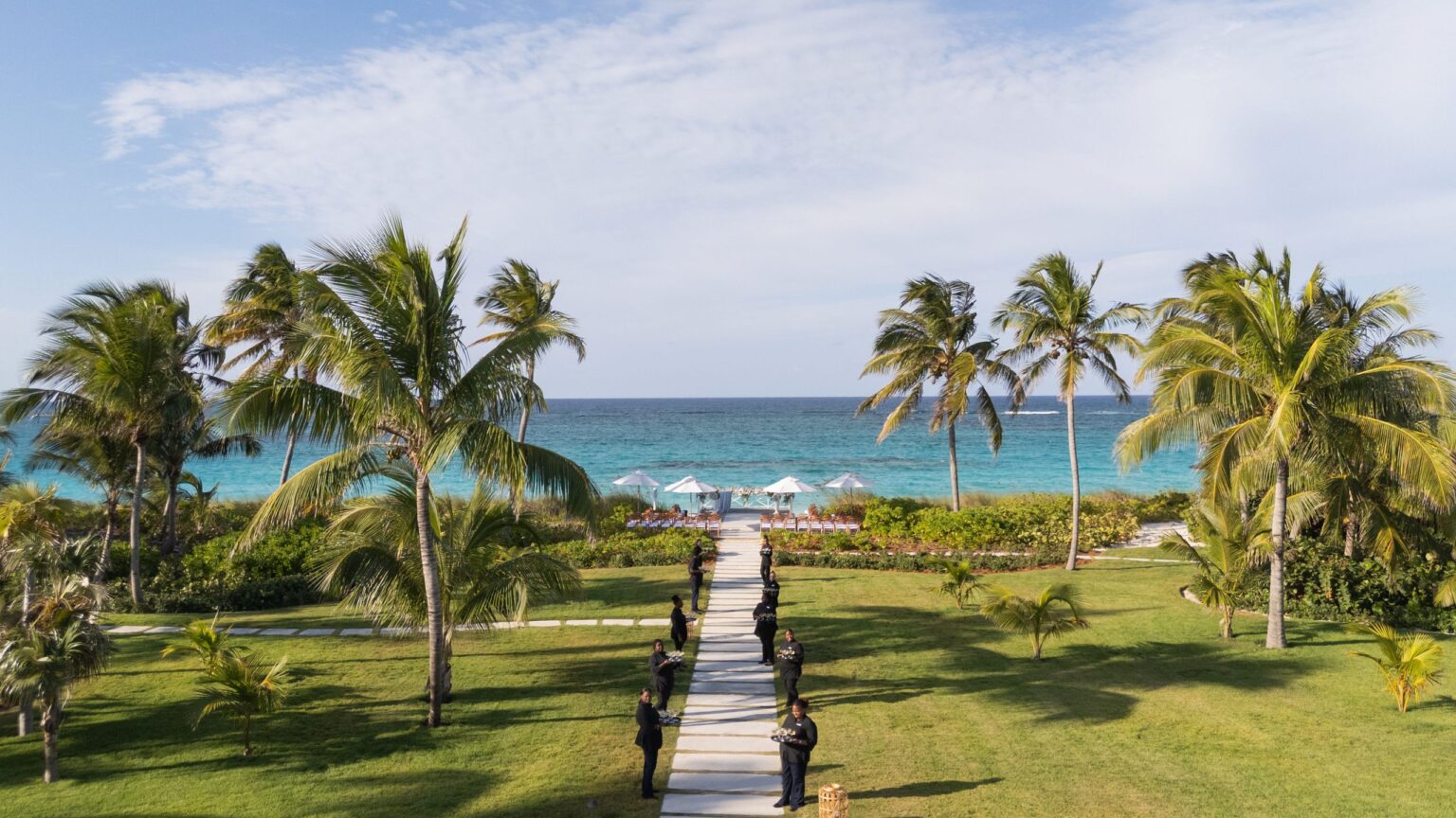 A ceremony aisle running across a lawn towards the sea