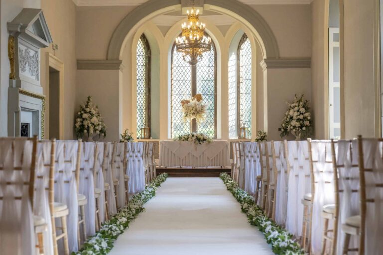 A Ballroom ceremony, a greenery-lined aisle to the registrar's table below the great arched window, Clearwell Castle