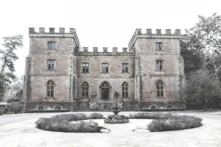 The castle's turreted facade on a frost-white winter morning, the circular drive and fountain before it, Clearwell Castle