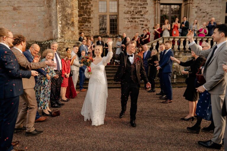 A confetti moment on the forecourt, the couple walking through guests before the castle steps, Clearwell Castle