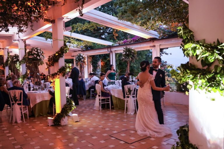 The first dance on a terrace beneath the pergola, with guests at their tables, Clorinda Bellone Elite Weddings