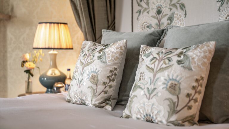 Detail of embroidered cushions and a table lamp in one of the castle bedrooms, Cluny Castle