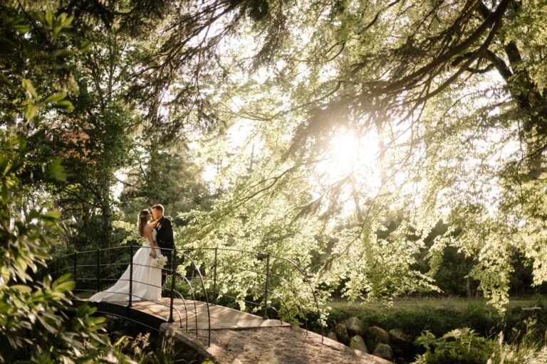 A couple on a footbridge in the woodland, with sunlight through the trees, Cluny Castle