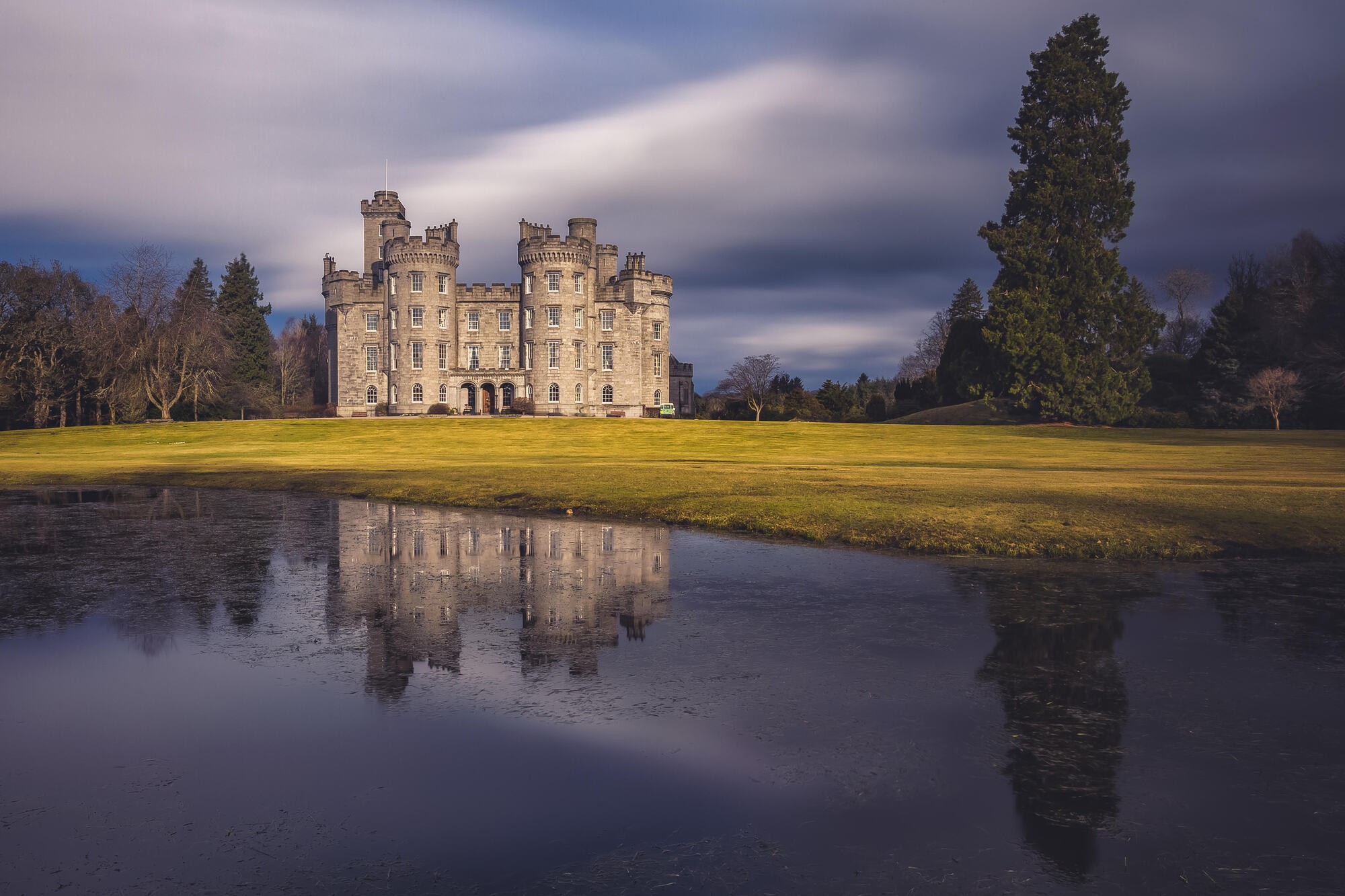 A long exposure of the castle and its reflection under a moving evening sky, Cluny Castle