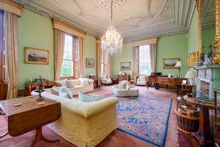 The Drawing Room, with green walls, an ornate plaster ceiling, a chandelier and tall sash windows, Cluny Castle