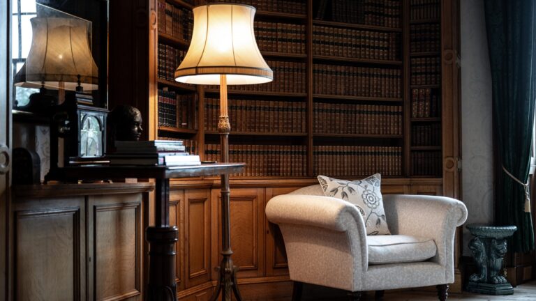 A reading corner in the Library, a standard lamp beside an armchair and shelves of leather-bound books, Cluny Castle