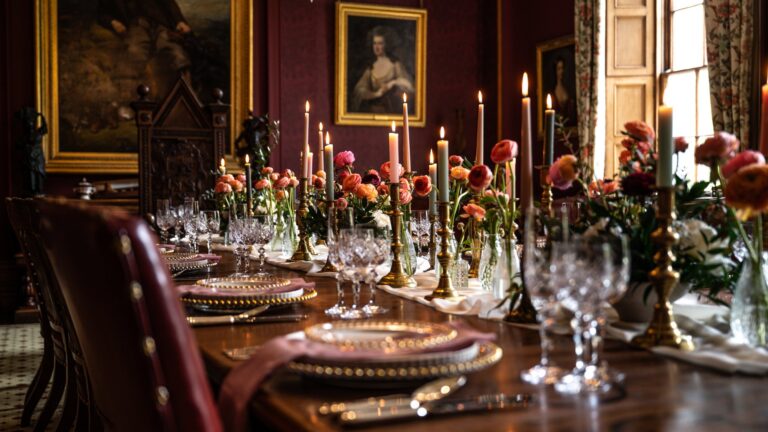 The Dining Room table set with candles, cut glass and ranunculus beneath family portraits, Cluny Castle