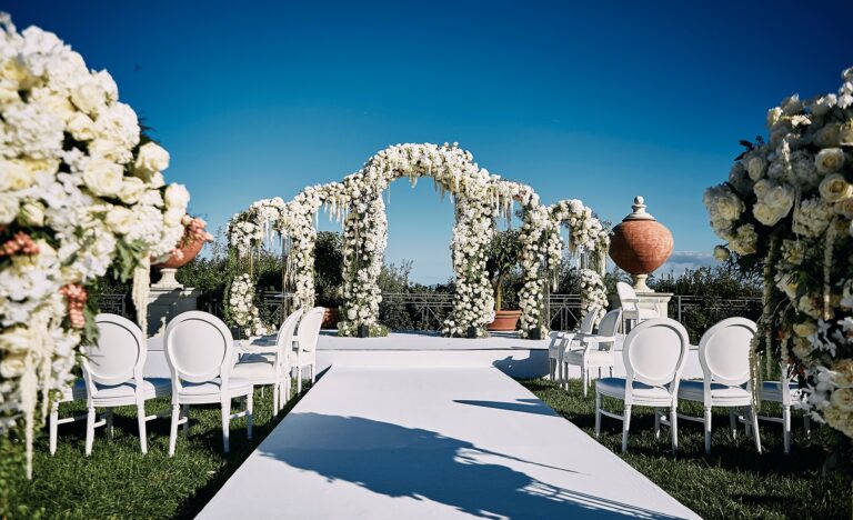 White aisle lined with chairs and floral arches in a garden, Cocoon Events