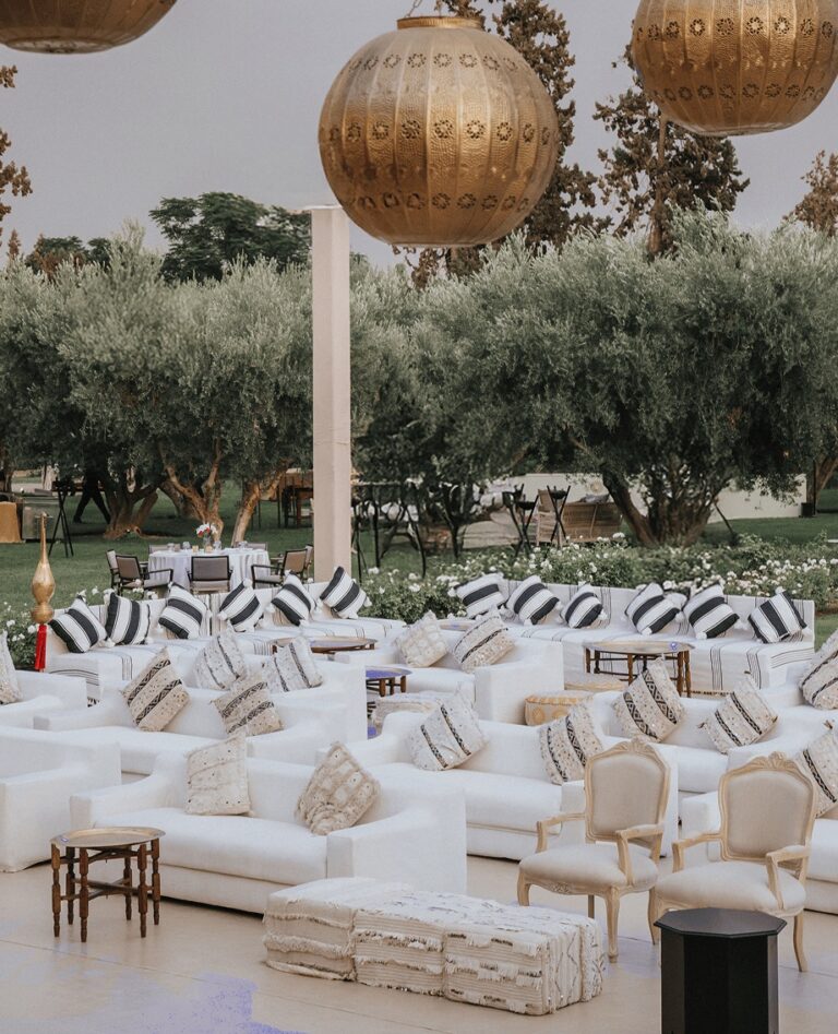 White lounge seating beneath brass lanterns among olive trees, Cocoon Events