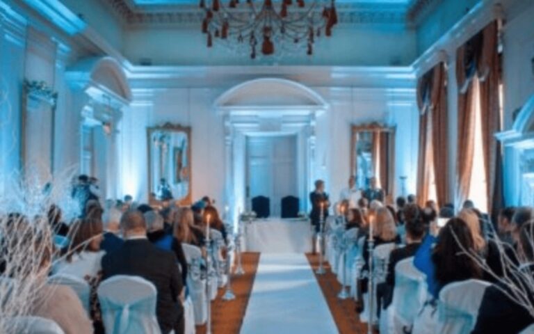 A ceremony hall lit in blue with chairs set either side of the aisle, Coombe Abbey