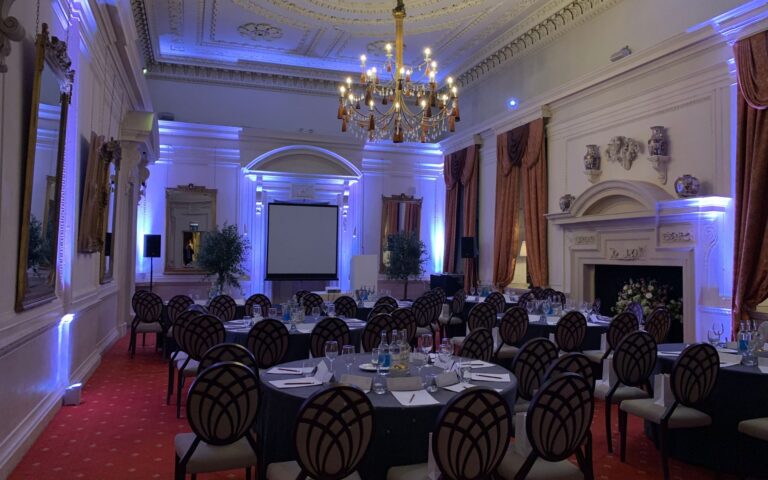 A reception room with tables laid and blue lighting, Coombe Abbey