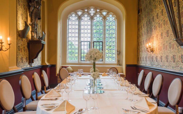 A long table laid in a Gothic-windowed room, Coombe Abbey