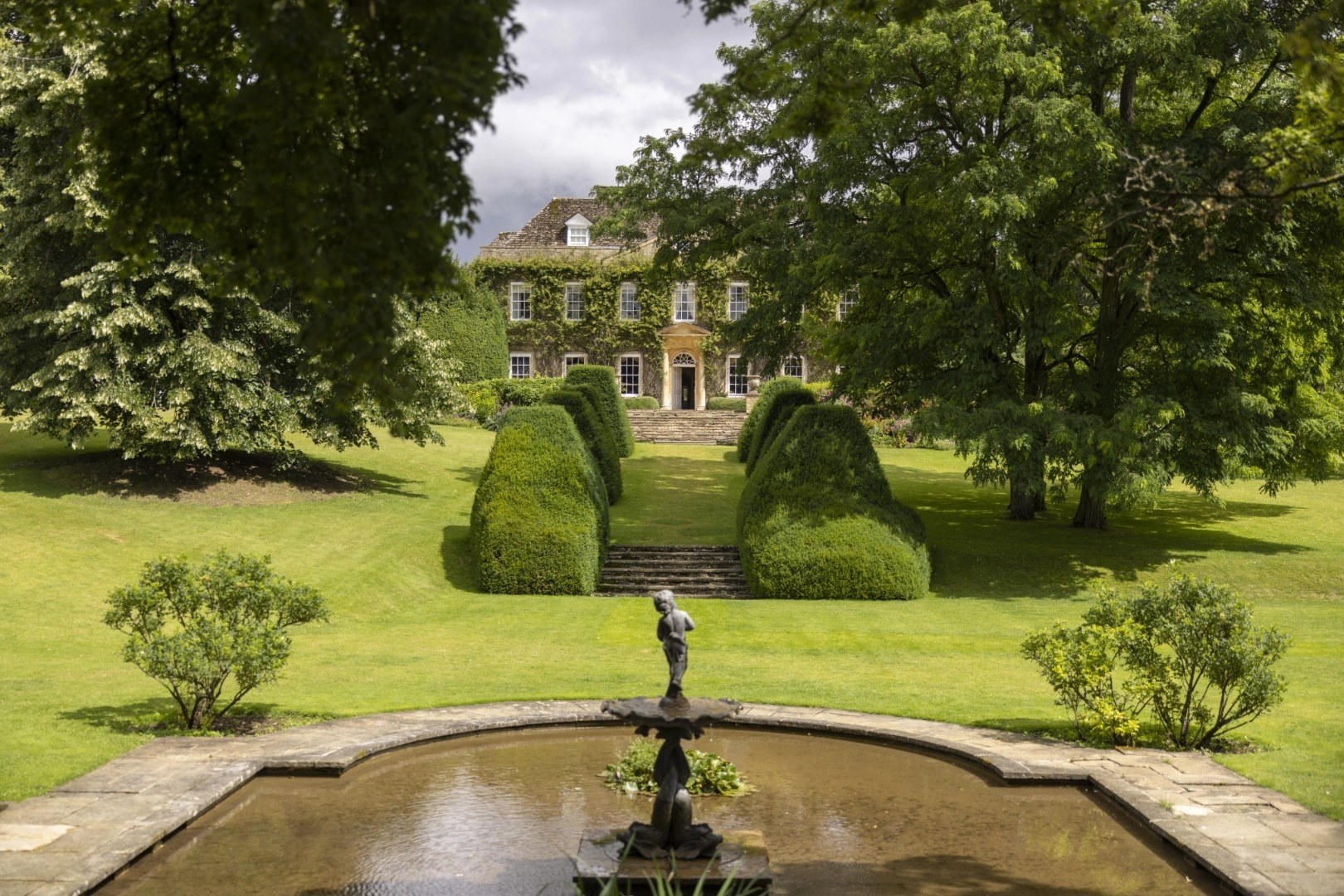 The manor seen over the fountain pool and clipped hedges, Cornwell Manor