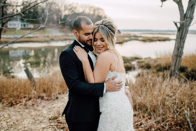 The couple embracing by the winter marshes, from a Christmas wedding at Three Village Inn, Long Island, Cottonwood Studios
