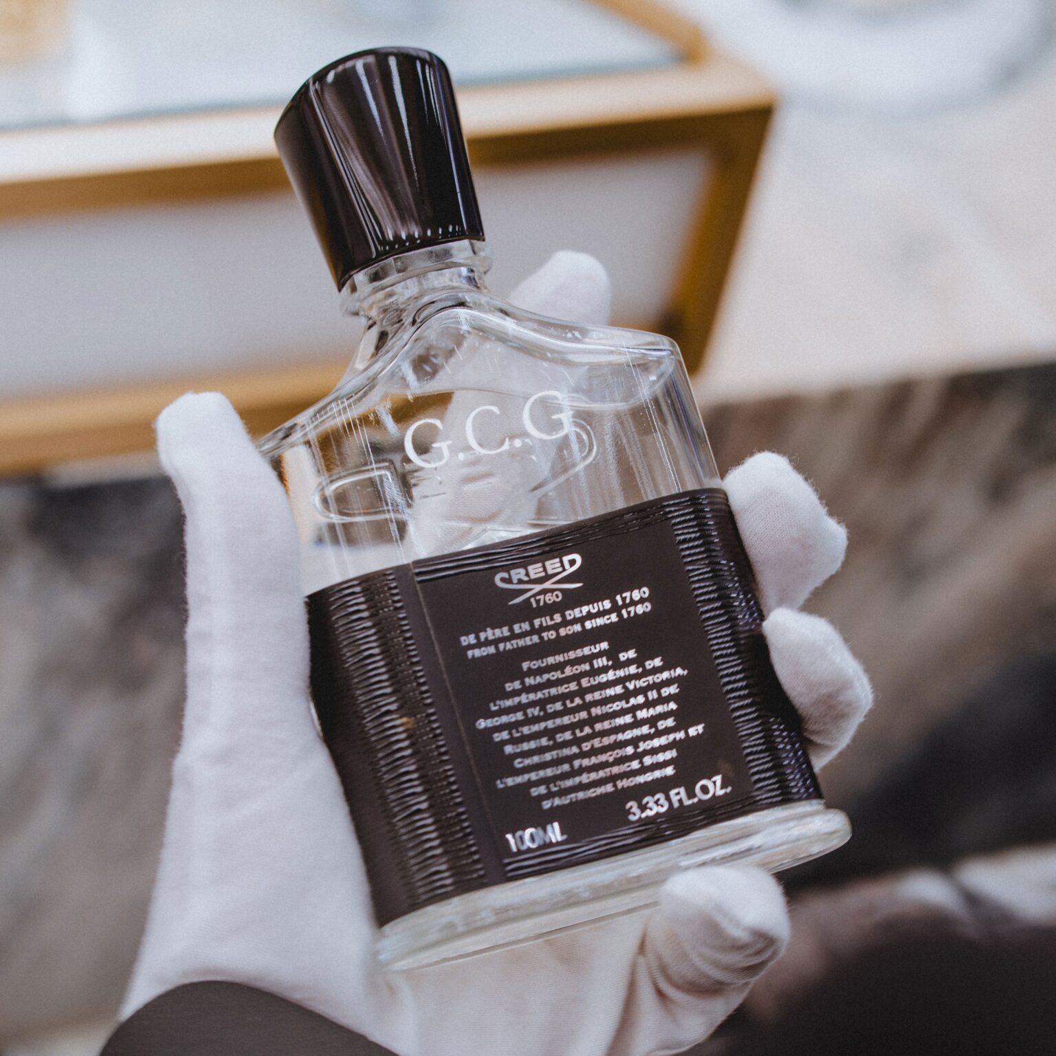 A gloved hand presents a bottle engraved with initials