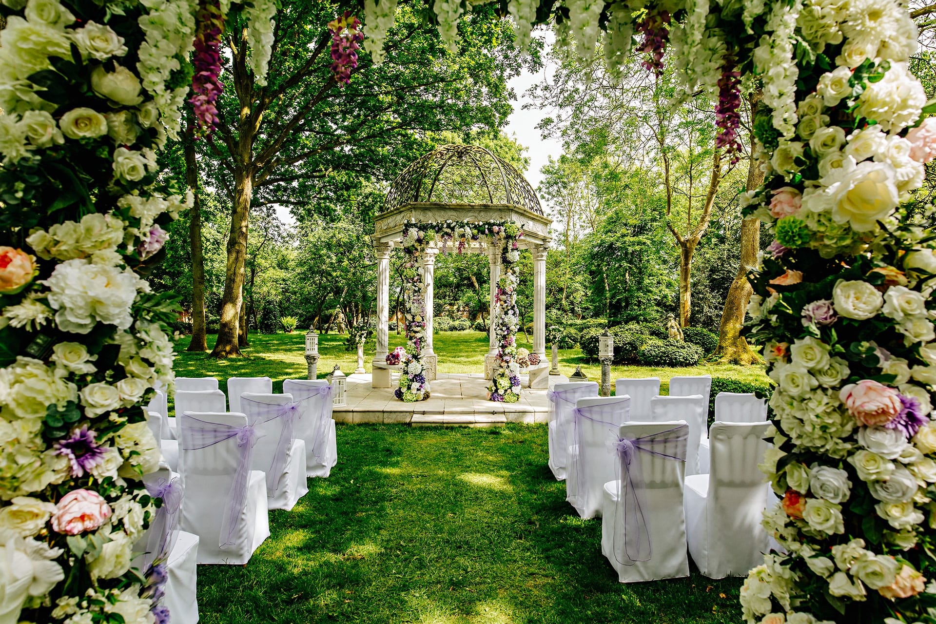 The marble gazebo in the orchard dressed for a ceremony, framed by a floral arch, Creeksea Place