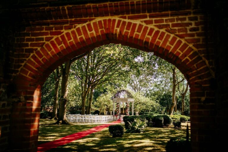 A Tudor brick archway framing the orchard gazebo and the red-carpet aisle beyond, Creeksea Place