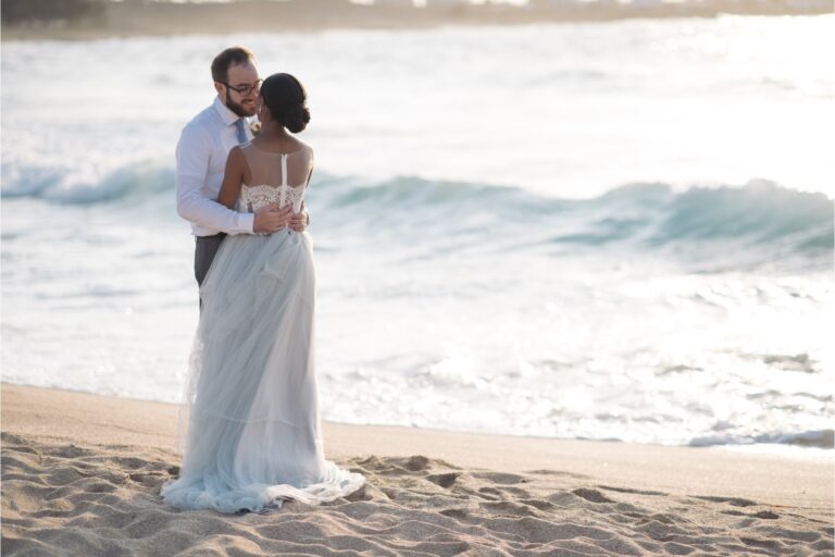 A couple embrace on a Cretan beach as waves roll in behind them, Crete for Love