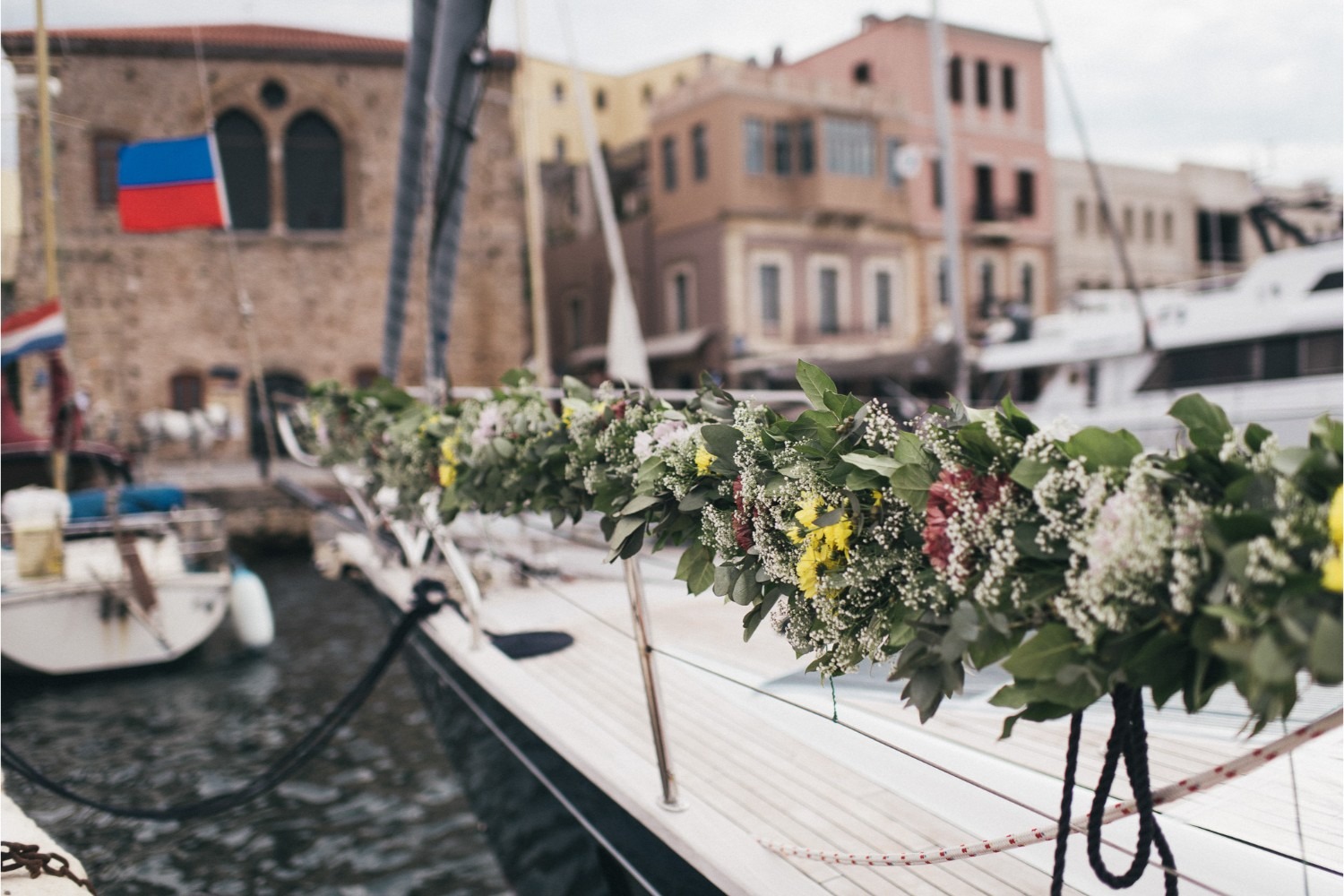 A flower garland tied along a yacht rail in Chania harbour for a vow renewal, Crete for Love