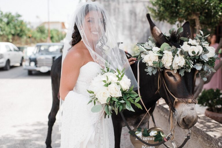 A bride in a veil beside a donkey dressed with white flowers, Crete for Love