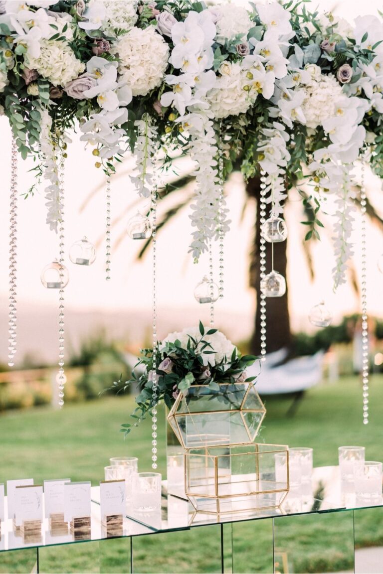 A hanging white floral installation above a mirrored table with candles, Crete for Love