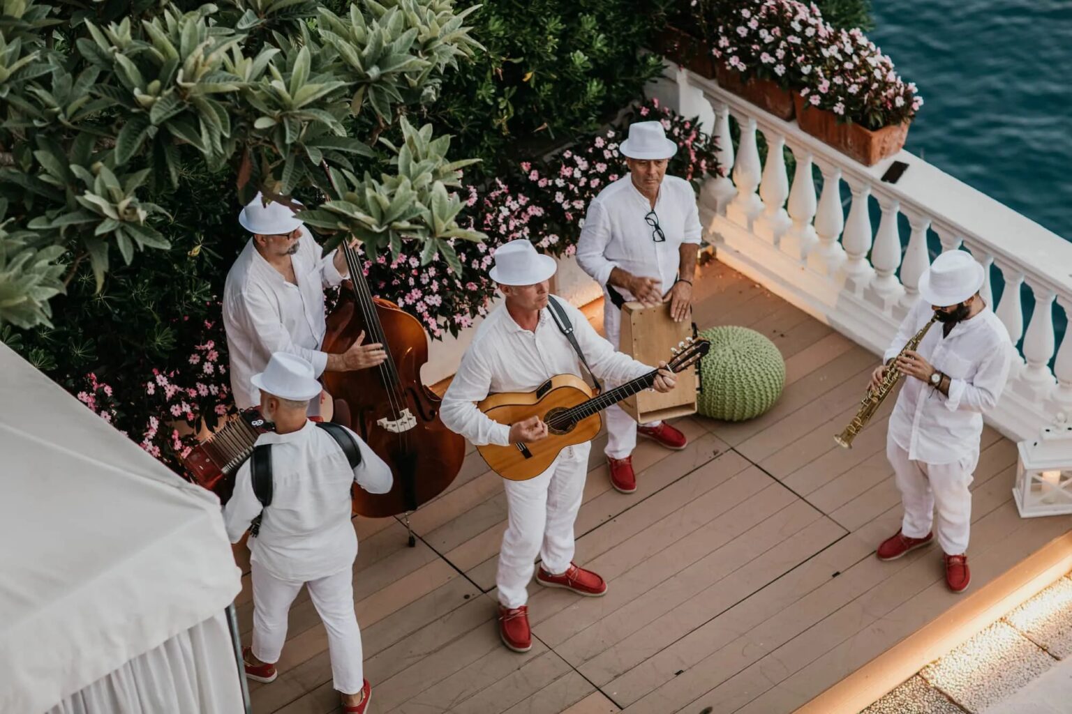 A band in white playing on a flower-lined terrace above the sea, Ravello