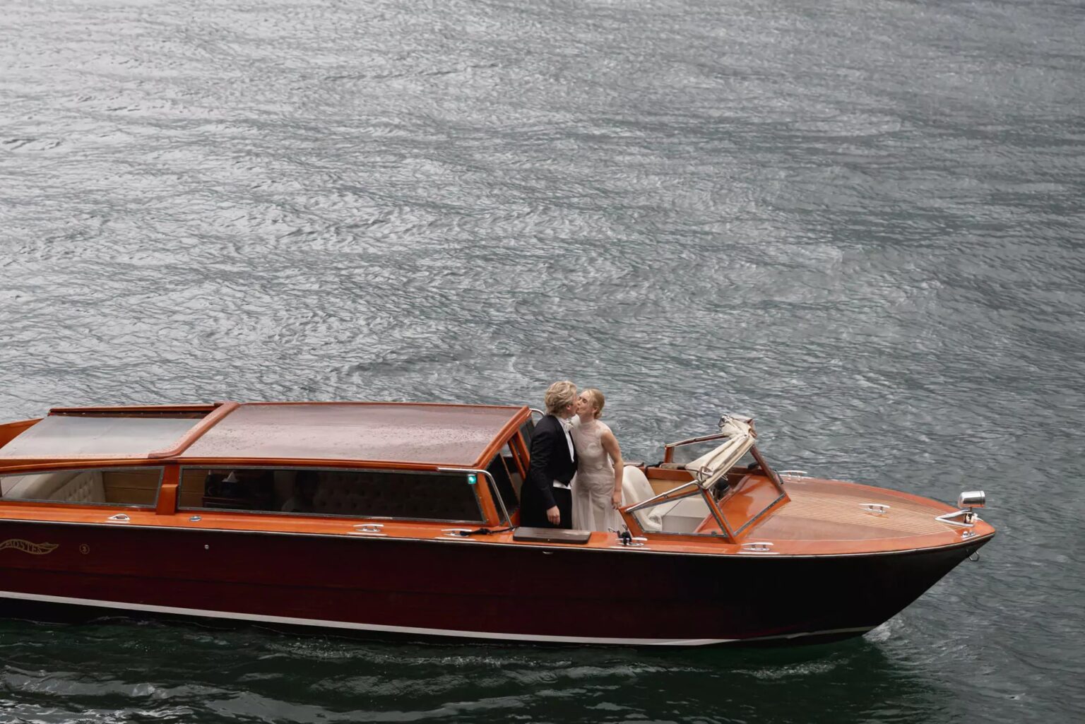 A couple crossing Lake Como in a varnished wooden launch