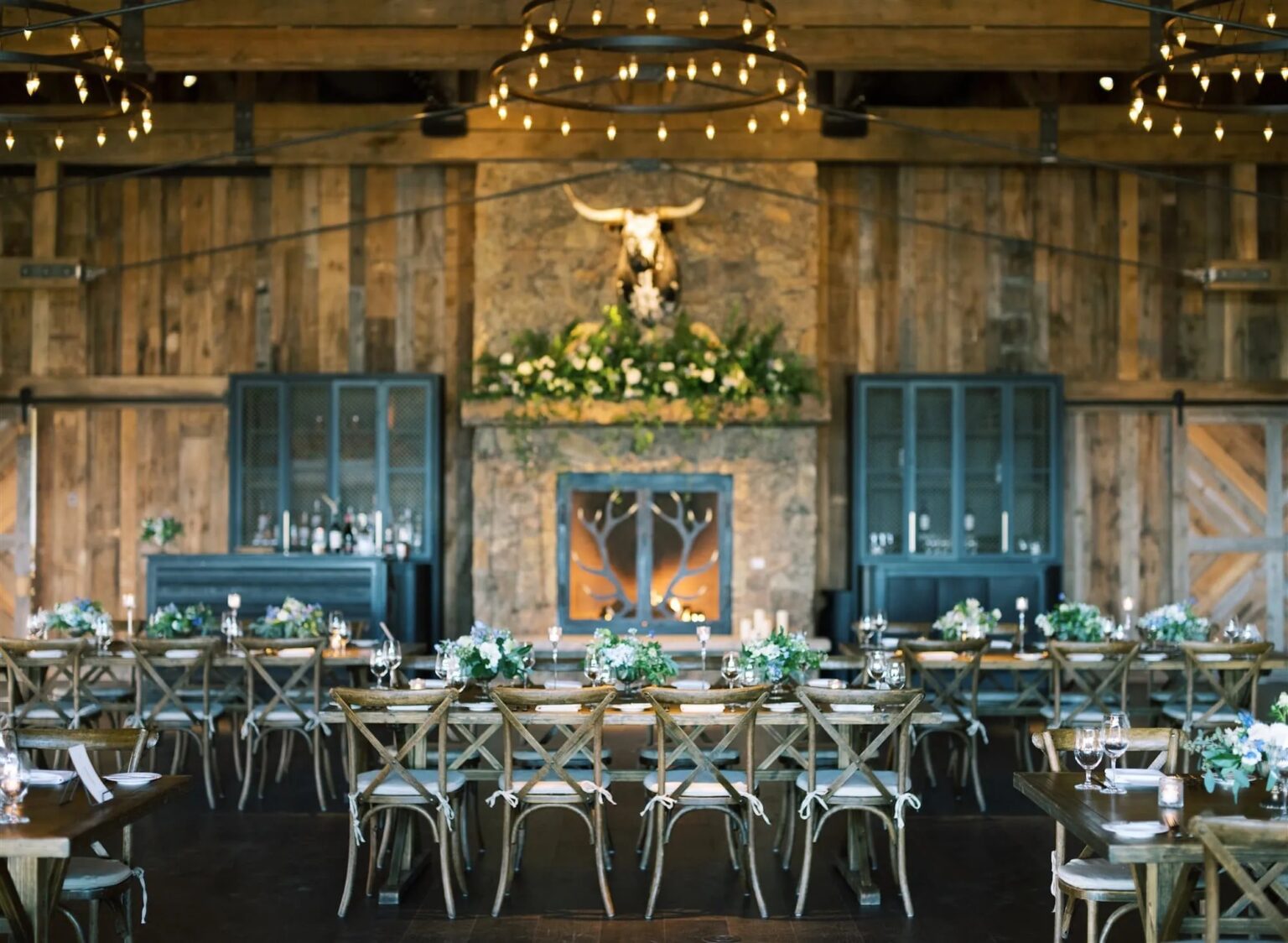 Barn reception with long tables, flowers and a stone fireplace, Wyoming, Cristina Verger Event Planning and Production