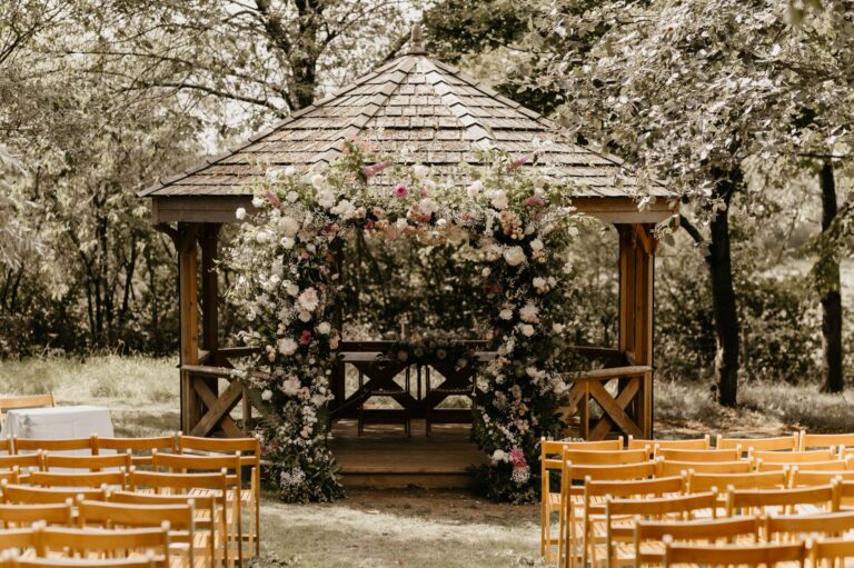 The Orchard Pavilion dressed with flowers, with wooden chairs set out for an outdoor ceremony, Crockwell Farm