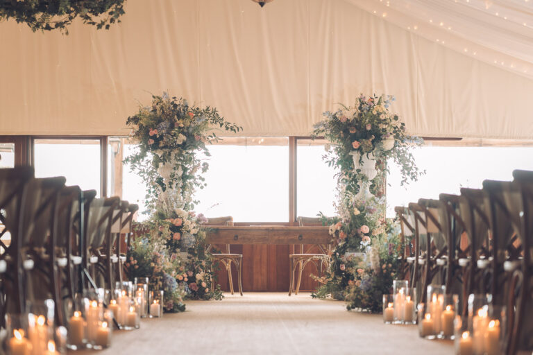 The starlit marquee arranged for a ceremony, with flower columns and candles lining the aisle, Crockwell Farm