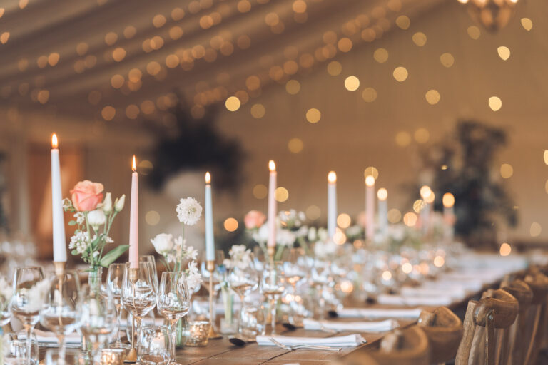Tapered candles, glassware and flowers along a long table in the marquee, Crockwell Farm
