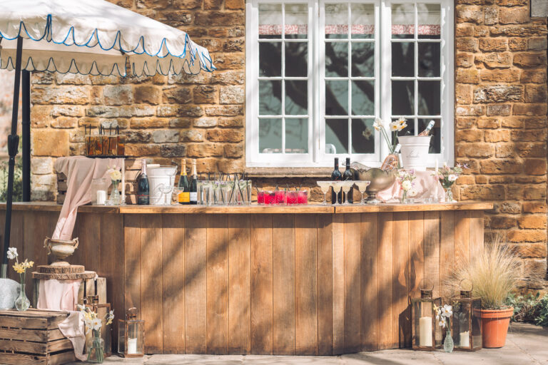 The outdoor bar against an ironstone wall, set with drinks under a scalloped parasol, Crockwell Farm