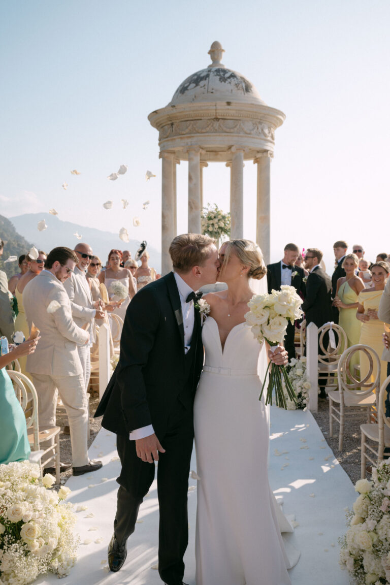 The first kiss on a white aisle with guests throwing petals, Cygnus Events