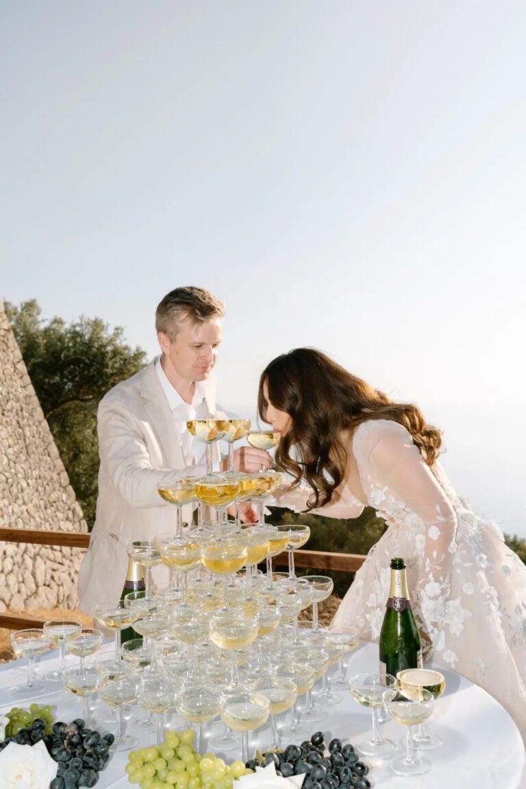 A couple pouring champagne over a coupe tower on a terrace, Cygnus Events